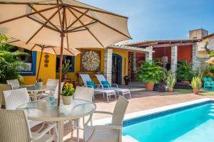 a patio with a table and chairs and a pool at Charme da Vila Suítes in Porto De Galinhas