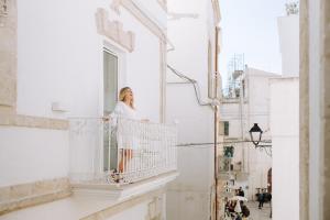 a woman standing on the balcony of a building at Dimora Anderì in Polignano a Mare