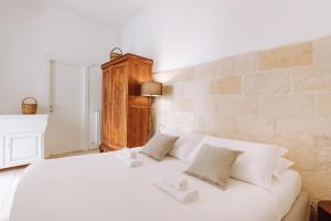 Cama blanca en habitación con pared de ladrillo en Dimora Anderì en Polignano a Mare