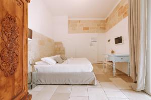 a white bedroom with a bed and a desk at Dimora Anderì in Polignano a Mare