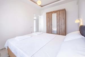 a white bedroom with a large bed and a door at Golden Rose Suit pension in Kaş