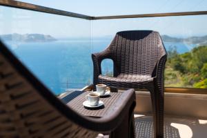 a chair and two cups on a table in front of a window at Golden Rose Suit pension in Kaş