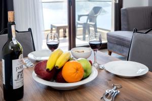 a table with a plate of fruit and two glasses of wine at Golden Rose Suit pension in Kaş
