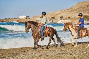 twee mensen die paardrijden op het strand bij Ultramare Superior Suites with Seaview in Mykonos-stad