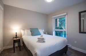 a bedroom with a large white bed with a window at Al's Escape by Revelstoke Vacations in Revelstoke