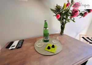 a table with a bottle and two glasses and flowers at Palazzo Raffaella Casa vacanze in Castel SantʼElia
