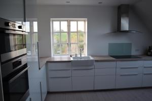 a white kitchen with a sink and a window at Villa Albeck in Rønde