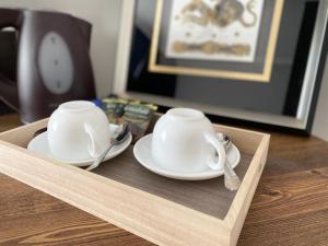 two white cups and saucers on a wooden tray at Aikol in Bishkek