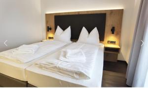 ein Schlafzimmer mit zwei Betten mit weißen Laken und Kissen in der Unterkunft Waldschlößl in Bruckmühl