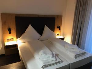 ein großes weißes Bett mit zwei Handtüchern darauf in der Unterkunft Waldschlößl in Bruckmühl