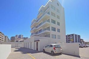 a white car parked in front of a building at Nautica 2 Bedroom Beachfront Apartment with Sea Views in Bloubergstrand