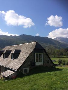 a stone house in a field with mountains in the background at Appartement dans grange in Aucun