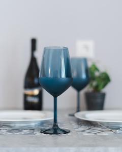 拉瑟的住宿－Nondas Apartments，桌子上两杯蓝色玻璃杯,配盘子和一瓶葡萄酒