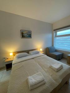 a bedroom with a large bed and a chair and a window at Apartman Dunav in Kladovo