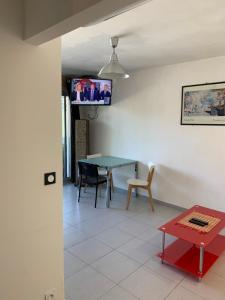 sala de estar con mesa y TV en la pared en Appartement en résidence climatisé avec parking, en Montpellier