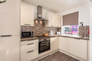 a kitchen with white cabinets and a microwave at Ayr Retreat - Donnini Apartments in Ayr