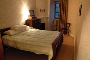 a bedroom with a bed and a dresser and a window at Butlers Quarters Apartment in Cairndow