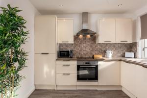 a kitchen with white cabinets and a black oven at Ayr Retreat - Donnini Apartments in Ayr +9 photos