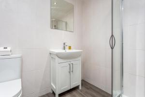 a white bathroom with a sink and a shower at Ayr Retreat - Donnini Apartments in Ayr