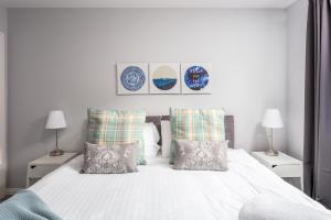 a bedroom with a white bed with pillows and two lamps at Ayr Retreat - Donnini Apartments in Ayr