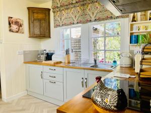a kitchen with white cabinets and a chicken sitting on a counter at Carnell Country Estate in Hurlford