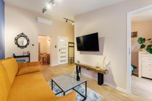 a living room with a couch and a tv on a wall at Apartamenty Greenpoint Dźwirzyno in Dźwirzyno