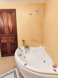 bañera blanca en el baño con puerta en Grande Grotta House, en Myrties