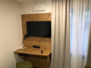 einen Flachbild-TV an einer Holzwand neben einem Vorhang in der Unterkunft Waldschlößl in Bruckmühl