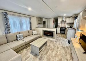 a living room with a couch and a fireplace at Luxury 3 bedroom caravan between Perranporth and Newquay, Cornwall in Newquay
