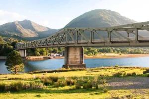 a bridge over a river with mountains in the background at Failte Mhor in Fort William +4 photos