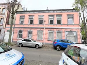 drie auto's geparkeerd voor een roze gebouw bij Wohnung in Düren Stadtmitte in Düren - Eifel