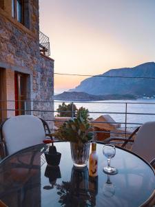 una mesa de cristal con un jarrón y copas de vino en el balcón en Grande Grotta House, en Myrties