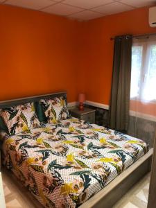 a bed in a bedroom with an orange wall at Habitations Amédée in Bouillante