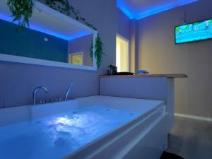 a bathroom with a tub with a tv on the wall at Cavaliere Suite in Bari