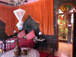 タフロウトにあるVilla Siliya maga Cœur vallée amlen tafraoutのベッドルーム1室(赤いカーテンとテーブル付きのベッド1台付)