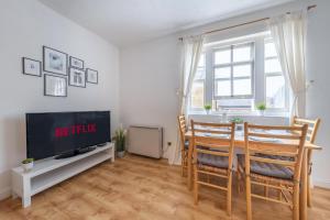 a living room with a table and chairs and a tv at Stansted Airport & Bishops Stortford Town Centre Professional Apartment in Bishops Stortford