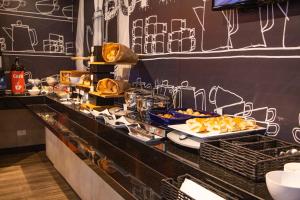 a buffet line with plates of food on a counter at ibis budget Curitiba Aeroporto in São José dos Pinhais