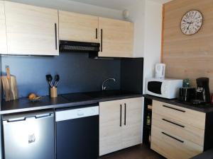 a kitchen with wooden cabinets and a clock on the wall at Appartement 2 Chambres au calme in Les Angles
