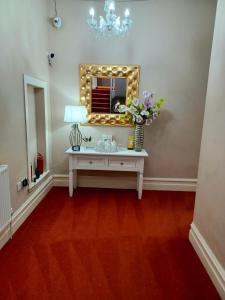 a dressing table with a mirror and flowers on it at Gabriel Guesthouse in Rhyl