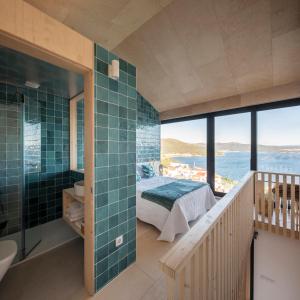 baño principal con ducha de azulejos verdes y cama en MIRAFLORES Alojamiento Turístico, en Muros