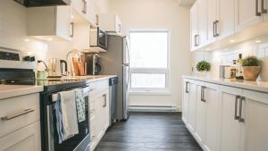 a kitchen with white cabinets and a wooden floor at The Revy Den by Revelstoke Vacations in Revelstoke