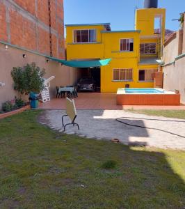 a backyard with a yellow house and a bench at Refugio del Turista in Tupiza