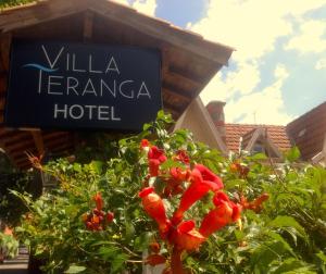 um sinal para um hotel ao lado de um arbusto com flores vermelhas em Hôtel Villa Teranga em Andernos-les-Bains