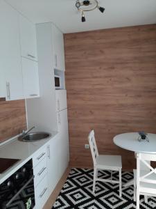 - une cuisine avec des placards blancs, une table et un évier dans l'établissement Apartman Poco, à Bijeljina