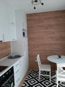 a kitchen with white cabinets and a table and a sink at Apartman Poco in Bijeljina