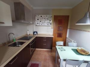 una cucina con lavandino e tavolo con sedie di EDIFICIO CINE MON a Burela de Cabo