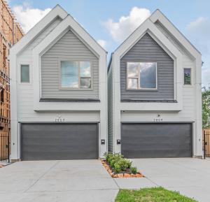 a white house with two garage doors at LUXURY 3BR, KS Bed mins away 4RM Dtown, med ctr in Houston