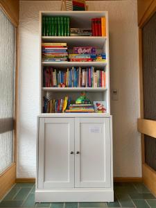 ein weißes Bücherregal mit Büchern darauf in der Unterkunft Ferienwohnungen Bachblick in Übersee