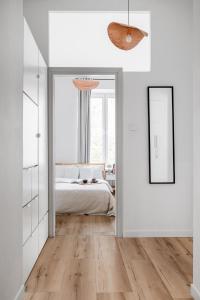 a white bedroom with a bed and a mirror at oompH Warsaw Nowy Swiat Apartment in Warsaw