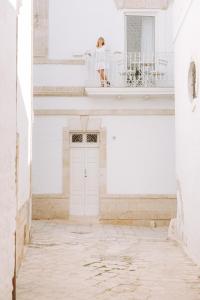 a woman standing on a balcony in a white building at Dimora Anderì in Polignano a Mare